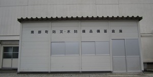 旧万沢中学校体育館裏側の防災備蓄倉庫外観の画像
